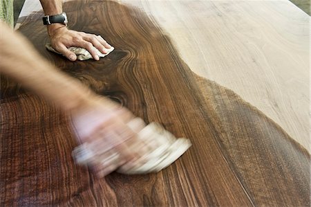 simsearch:6118-08521776,k - Caucasian man factory worker applying finish to a recycled wood table top in a woodworking factory Stock Photo - Premium Royalty-Free, Code: 6118-09140158