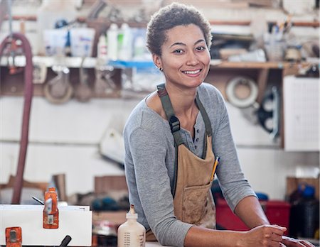 View of a smiling black woman factory worker at her work station in a woodworking factory. Foto de stock - Sin royalties Premium, Código: 6118-09140133
