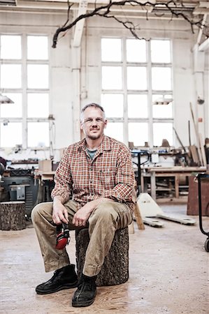 Caucasian man factory worker sitting on a stool in a woodworking factory. Stock Photo - Premium Royalty-Free, Code: 6118-09140131