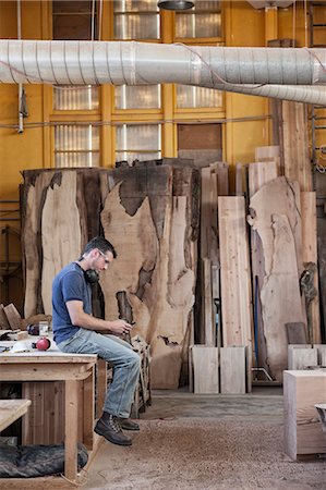 Caucasian man factory worker taking a break checking phone messages in a woodworking factory. Foto de stock - Sin royalties Premium, Código: 6118-09140138