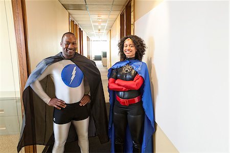 A man and woman team of black office super hero's standing in a hallway of their office. Stock Photo - Premium Royalty-Free, Code: 6118-09148017