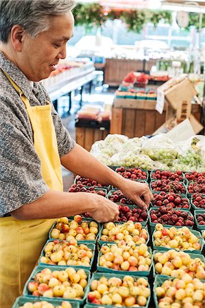 simsearch:614-06169178,k - Man wearing apron standing at stall with punnets of fresh cherries at a fruit and vegetable market. Stock Photo - Premium Royalty-Free, Code: 6118-09148112