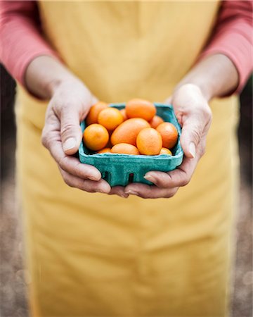 simsearch:614-06169178,k - High angle close up of person holding punnet of fresh orange tomatoes at a fruit and vegetable market. Stock Photo - Premium Royalty-Free, Code: 6118-09148117