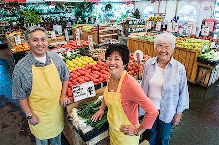 simsearch:614-06169178,k - High angle view of man and two women wearing aprons standing at stall with fresh tomatoes at a fruit and vegetable market. Stock Photo - Premium Royalty-Free, Code: 6118-09148127
