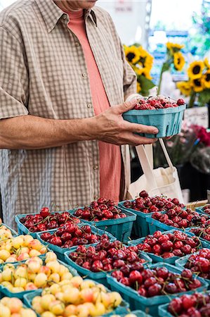 simsearch:614-06169178,k - Man standing at stall, holding punnet with fresh cherries at a fruit and vegetable market. Stock Photo - Premium Royalty-Free, Code: 6118-09148125