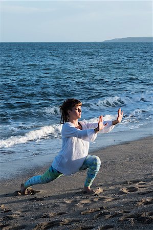 simsearch:6118-07731916,k - Young woman with brown hair wearing white blouse standing on a beach by the ocean, doing Tai Chi. Photographie de stock - Premium Libres de Droits, Code: 6118-09165857