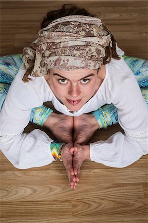 simsearch:400-04435419,k - High angle view of woman wearing white blouse and headscarf sitting on floor in yoga pose, looking at camera. Stock Photo - Premium Royalty-Free, Code: 6118-09165864