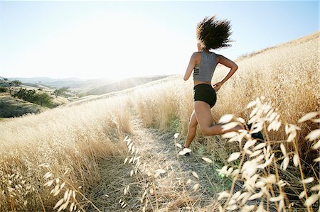 simsearch:6118-08140197,k - Young woman with curly brown hair running in urban park. Stock Photo - Premium Royalty-Free, Code: 6118-09165967