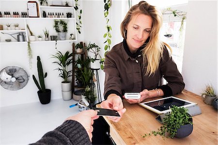 simsearch:6118-08202525,k - Female owner of plant shop receiving credit card from customer for payment of small String of Pearls plant in black pot. Stock Photo - Premium Royalty-Free, Code: 6118-09165910