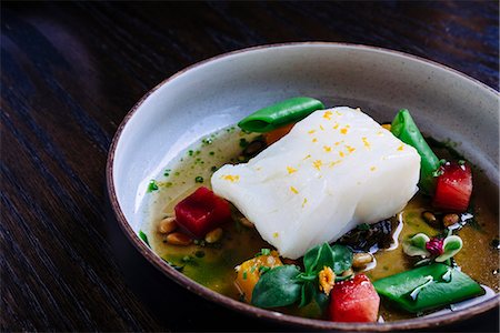 simsearch:6118-07808971,k - Pouring broth on halibut with lemon, peas, melon, beets and herbs Stock Photo - Premium Royalty-Free, Code: 6118-09174501