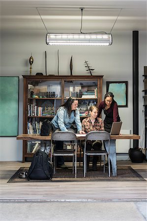 simsearch:6118-08660009,k - Three women gathered around table in office area of a metal workshop. Stock Photo - Premium Royalty-Free, Code: 6118-09111997