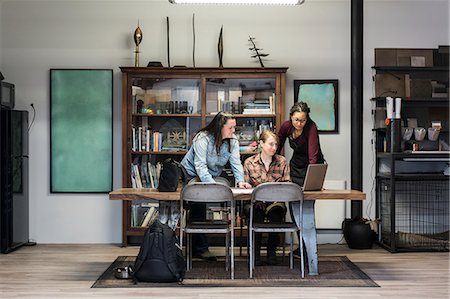 simsearch:6118-08660009,k - Three women gathered around table in office area of a metal workshop. Stock Photo - Premium Royalty-Free, Code: 6118-09111998
