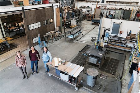 simsearch:6118-08660009,k - High angle view of three women standing in metal workshop, looking at camera. Stock Photo - Premium Royalty-Free, Code: 6118-09112026