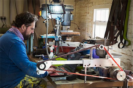 electric sander - A craftsman sitting at table in a workshop, using laptop computer, typing among the cluttered on the workbench. Stock Photo - Premium Royalty-Free, Code: 6118-09112129