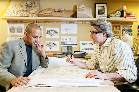 A multi-ethnic team of two male architects working on plans for a new home in an architect's office. Stock Photo - Premium Royalty-Free, Code: 6118-09129483