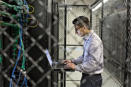 Hispanic man technician doing diagnostic tests on computer servers in a large server farm. Photographie de stock - Premium Libres de Droits, Code: 6118-09129875
