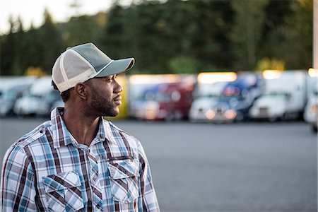 Black man truck driver near his truck parked in a parking lot at a truck stop Stock Photo - Premium Royalty-Free, Code: 6118-09139347