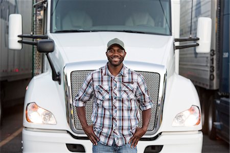 Black man truck driver near his truck parked in a parking lot at a truck stop Stock Photo - Premium Royalty-Free, Code: 6118-09139372