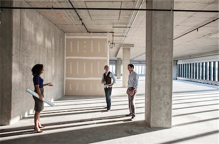 Mixed race team of business people touring a new empty raw office space. Stock Photo - Premium Royalty-Free, Code: 6118-09139442