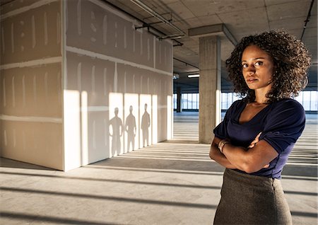 Black businesswoman  standing in an empty raw office space. Stock Photo - Premium Royalty-Free, Code: 6118-09139445