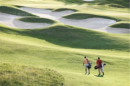 View from above of two golfers walking on a fairway toward the green of a golf course. Foto de stock - Sin royalties Premium, Código: 6118-09139705