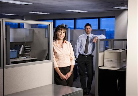 Two young business people working into the evening in a cubicle office set up. Stock Photo - Premium Royalty-Free, Code: 6118-09139814