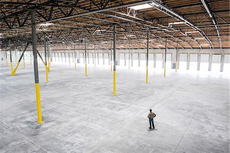 depot - Owner checking out the new interior of a large empty warehouse space. Stock Photo - Premium Royalty-Free, Code: 6118-09139941