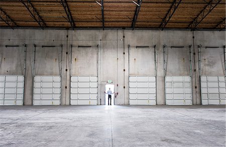 depot - Man standing doorway of new warehouse waiting for the arrival of the fist truck with new business. Stock Photo - Premium Royalty-Free, Code: 6118-09139966