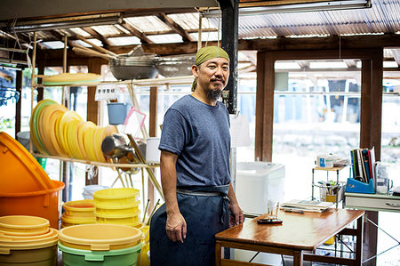 Japanese man wearing bandana standing in a textile plant dye workshop, smiling at camera. Stock Photo - Premium Royalty-Free, Code: 6118-09200458