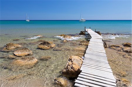 Wooden pier and clear turquoise sea with yachts at Provatas beach, Milos, Cyclades, Aegean Sea, Greek Islands, Greece, Europe Stock Photo - Premium Royalty-Free, Code: 6119-09161981