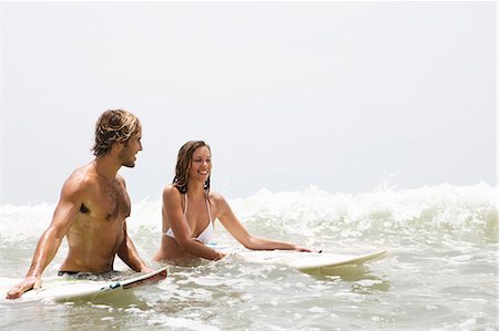 surf couple - Guy and girl in water with surfboards laughing Photographie de stock - Premium Libres de Droits, Code: 6122-07693304