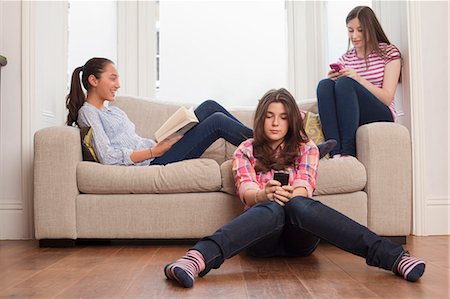 simsearch:6113-07731119,k - teenage girls sitting on sofa reading , checking messages Stock Photo - Premium Royalty-Free, Code: 6122-07693962
