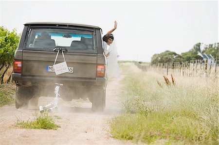 Newlywed woman waving from vehicle Stock Photo - Premium Royalty-Free, Code: 6122-07694090