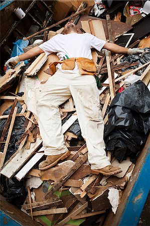 Man lying on top of pile of rubble in skip Stock Photo - Premium Royalty-Free, Code: 6122-07695849