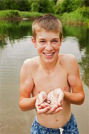 person holding snake - Teenage boy holding small reptile in hands by lake Stock Photo - Premium Royalty-Free, Code: 6122-07697540