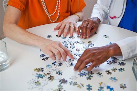 senior woman and doctor and two people - Senior woman and doctor with jigsaw puzzle Stock Photo - Premium Royalty-Free, Code: 6122-07697643