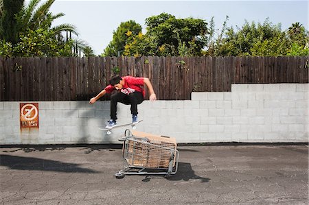 Man on skateboard jumping over a shopping trolley Photographie de stock - Premium Libres de Droits, Code: 6122-07697724