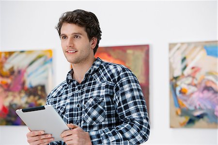 Young man using digital tablet in art gallery Stock Photo - Premium Royalty-Free, Code: 6122-07698333