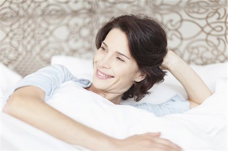 Smiling woman sitting up in bed Stock Photo - Premium Royalty-Free, Code: 6122-07701605