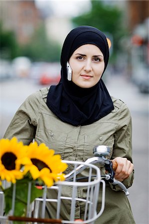 Woman in headscarf biking on cell phone Stock Photo - Premium Royalty-Free, Code: 6122-07701943