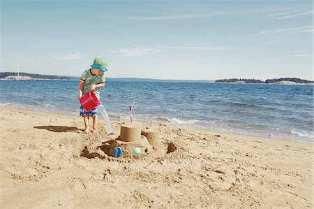 sand castle - Child making moat around sandcastle Stock Photo - Premium Royalty-Free, Code: 6122-07702190