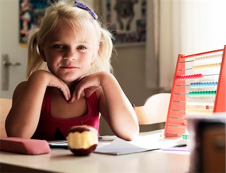 Girl sitting at desk with apple Stock Photo - Premium Royalty-Free, Code: 6122-07702292