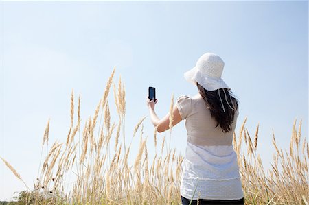Woman taking pictures with cell phone Stock Photo - Premium Royalty-Free, Code: 6122-07703533