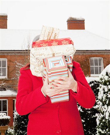 Woman carrying wrapped gifts in snow Stock Photo - Premium Royalty-Free, Code: 6122-07704058