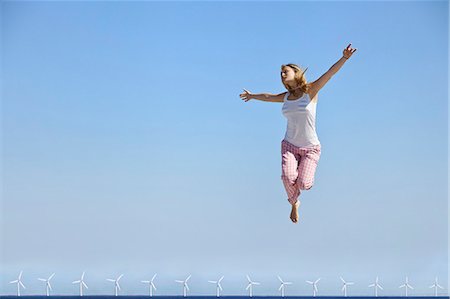 Woman jumping for joy over wind turbines Photographie de stock - Premium Libres de Droits, Code: 6122-07705917