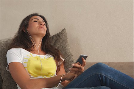 Woman listening to headphones on sofa Stock Photo - Premium Royalty-Free, Code: 6122-07707160