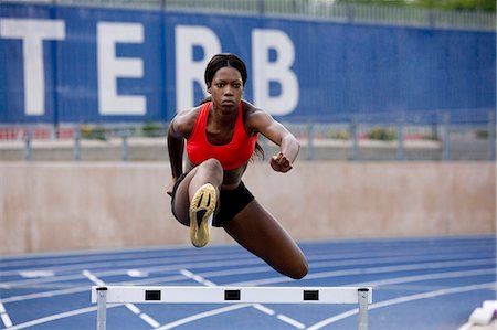 simsearch:6113-07588693,k - Runner jumping over hurdles on track Stock Photo - Premium Royalty-Free, Code: 6122-08212260