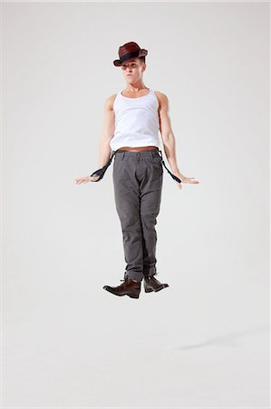 dancing white background - Dancer jumping in the air while holding trouser braces Stock Photo - Premium Royalty-Free, Code: 6122-08212735