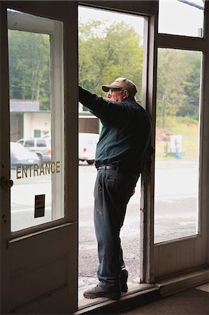 Senior man in doorway of store, looking out Stock Photo - Premium Royalty-Free, Code: 6122-08212890