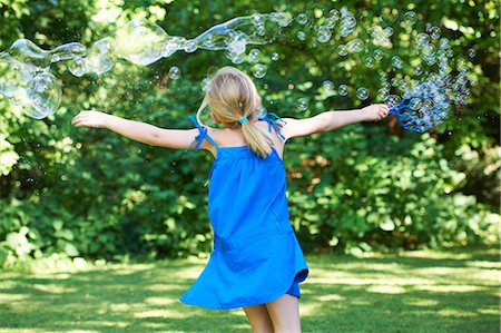 Girl playing with bubbles in backyard Stock Photo - Premium Royalty-Free, Code: 6122-08229051